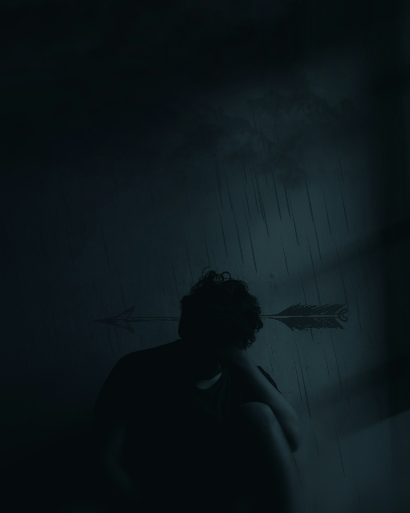Un homme assis dans le noir, la tête dans les mains