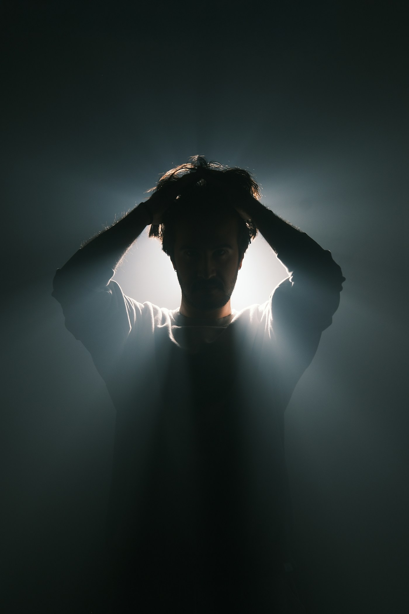 Un homme dans l'ombre, les mains sur la tête